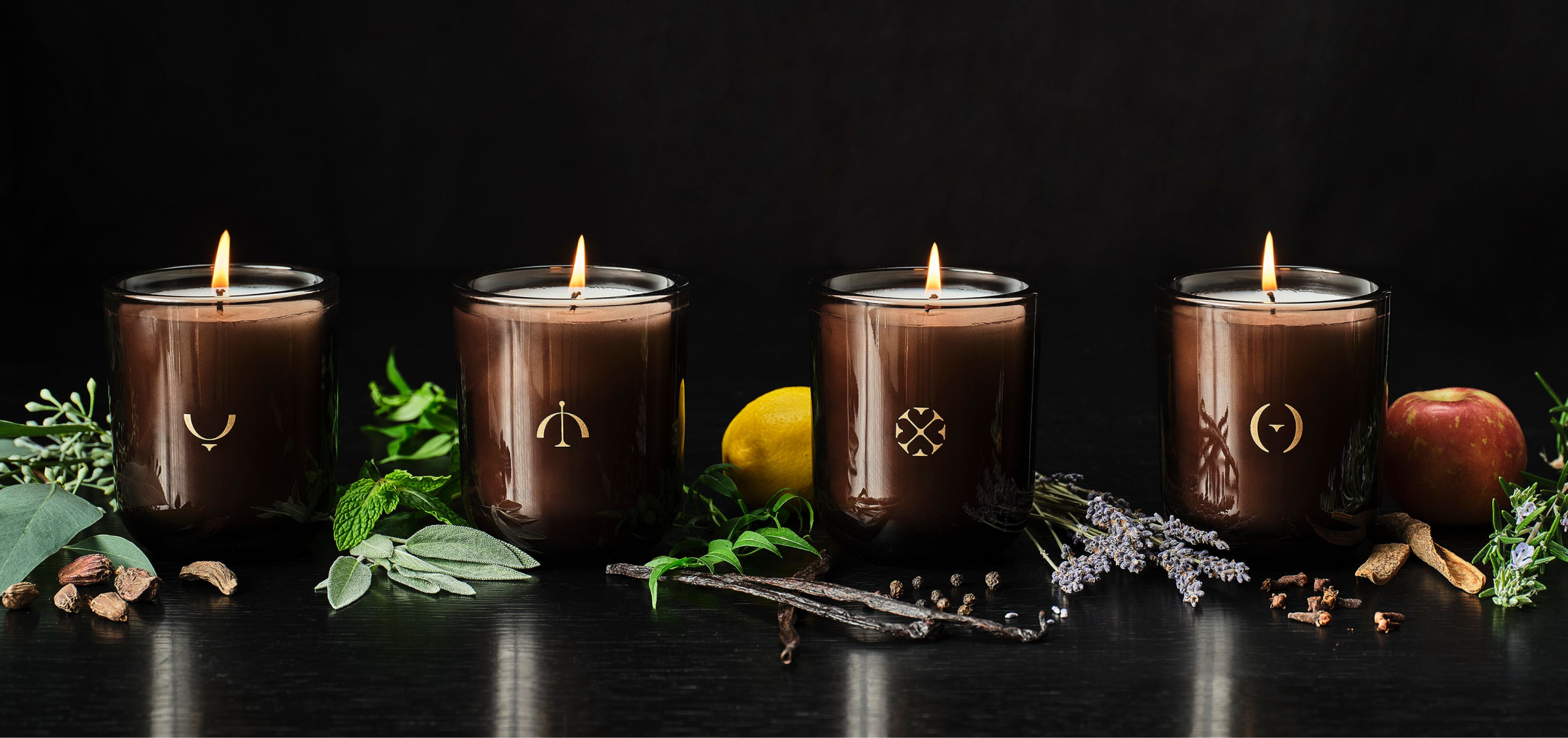 Photo of 4 seasonal candles with ingredients of their scents next to them
